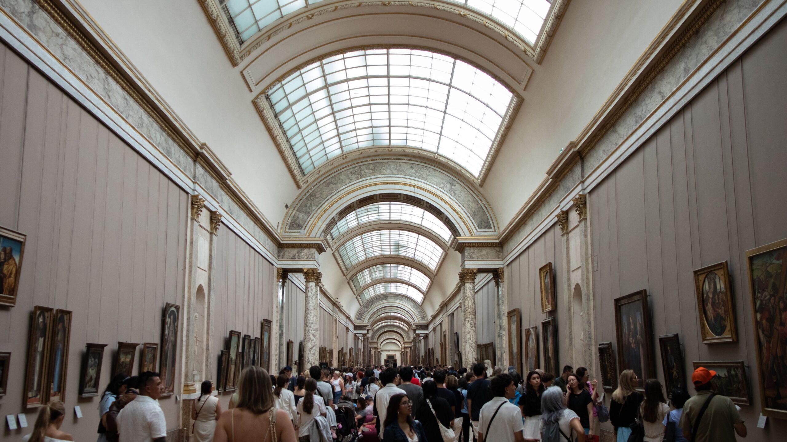 A busy corridor of the Louvre Museum in Paris showcasing art with visitors exploring the exhibits.