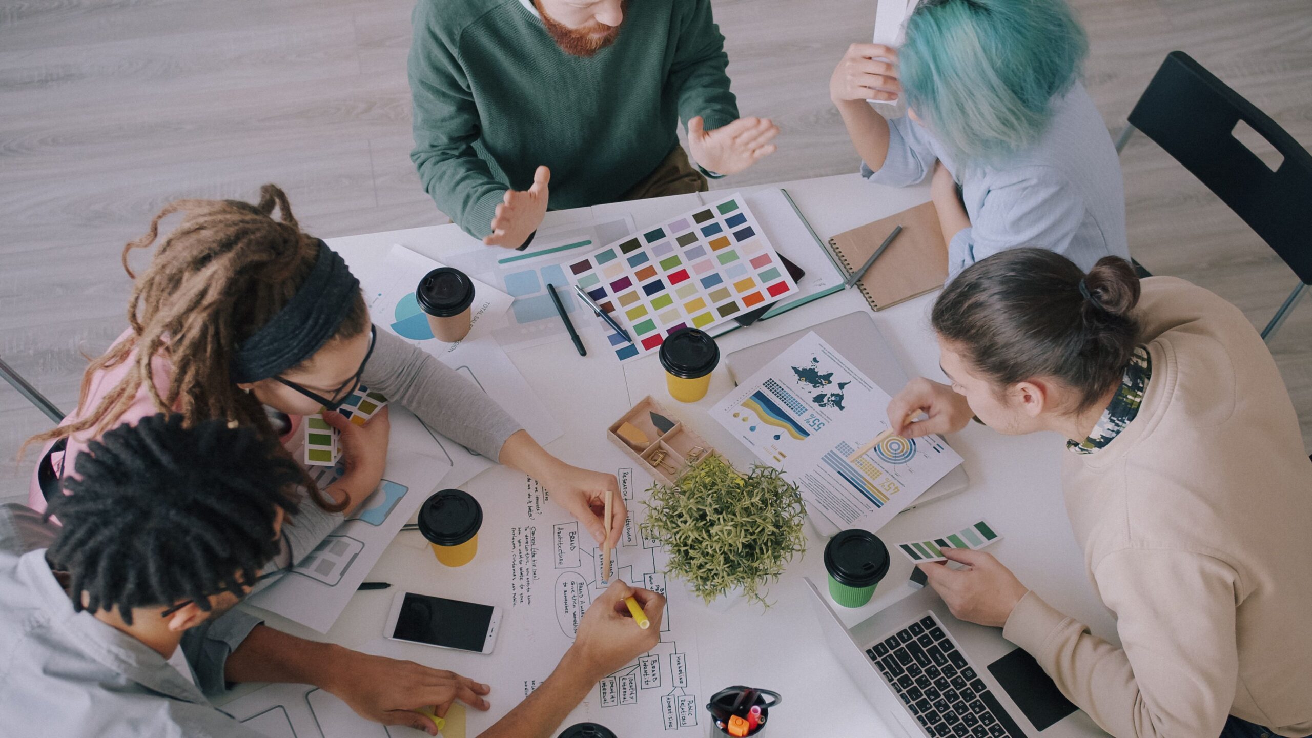 Creative team discusses design projects using color swatches and charts in office.